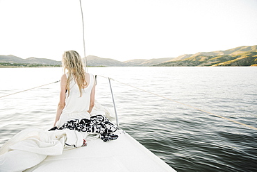 Blond teenage girl sitting on sail boat.