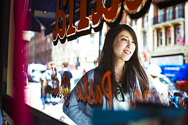 Young Japanese enjoying a day out in London, walking past a shop window, United Kingdom