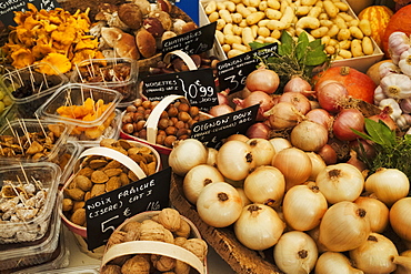 A market stall with display of fresh vegetables, onions, potatoes, walnuts and mushrooms, France