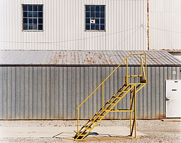 A ladder beside an industrial unit, with corrugated iron walls, USA