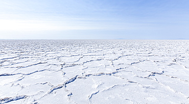 Cracked earth in a desert landscape against a blue sky.