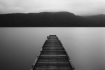 Wooden pier stretching out into the water at Towada Lake with mountains in the distance, Aomori, Japan