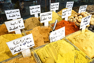 Close up of spices at a market, bright yellow and orange powders, seeds and nuts with signs, Amman, Jordan