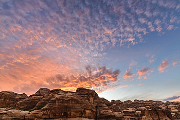 Rock formations in the Wadi Rum desert wilderness in southern Jordan at sunset, and the sun's rays reflected in light cloud, Wadi Rum, Jordan