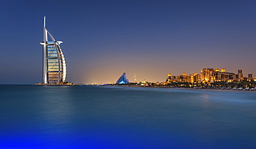 Cityscape of Dubai, United Arab Emirates at dusk, coastline of Persian Gulf with illuminated Burj Al Arab skyscraper in the distance, Dubai, United Arab Emirates