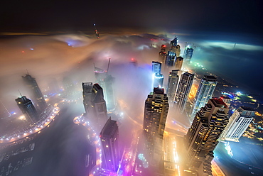 Aerial view of cityscape with illuminated skyscrapers above the clouds in Dubai, United Arab Emirates at dusk, Dubai, United Arab Emirates