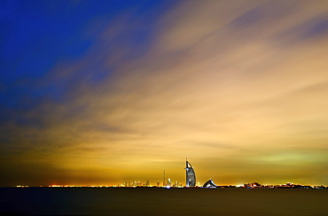 Cityscape of Dubai, United Arab Emirates at dusk with illuminated Burj Al Arab skyscraper in the distance, Dubai, United Arab Emirates