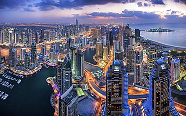 Aerial view of the cityscape of Dubai, United Arab Emirates at dusk, with illuminated skyscrapers and the marina in the foreground, Dubai, United Arab Emirates