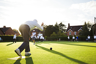 A lawn bowls player standing on a small yellow mat preparing to deliver a bowl down the green, the smooth grass playing surface, England, United Kingdom