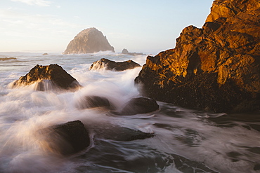 Seascape with breaking waves over rocks at dusk.