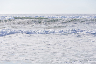 Seascape with breaking waves on sandy beach.