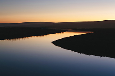 The open spaces of marshland and water channels. Flat calm water.  Dusk.