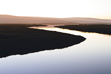 The open spaces of marshland and water channels. Flat calm water.  Dusk.