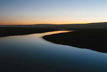 The open spaces of marshland and water channels. Flat calm water.  Dusk.