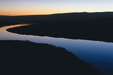 The open spaces of marshland and water channels. Flat calm water.  Dusk.