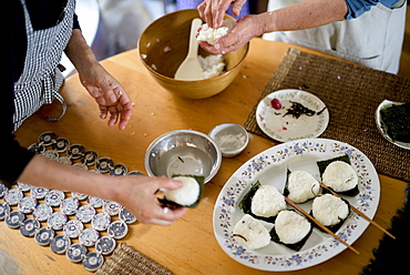 High angle close up of two women standing at a table, preparing plate of sushi, Japan