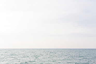 The view across a lake, a grey water surface, a view to the horizon and light cloudy sky, United States of America