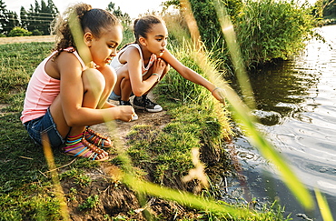 Girls playing by the edge of a lake in a park, United States of America