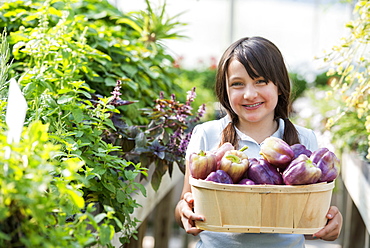 Summer on an organic farm. A girl holding a basket of fresh bell peppers.