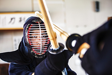 Close up of Japanese Kendo fighter wearing Kendo mask in combat pose, Kyushu, Japan