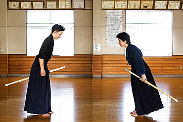 Female and male Japanese Kendo fighters standing opposite each other on wooden floor, bowing and greeting, Kyushu, Japan