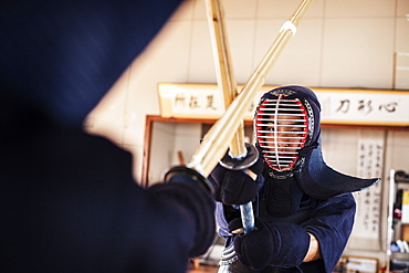 Two Japanese Kendo fighters wearing Kendo masks practicing with wood sword in gym, Kyushu, Japan