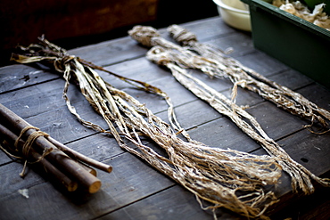 Small bunches of branches and plant fibres on a table, the organic matter used in making washi paper, Kyushu, Japan