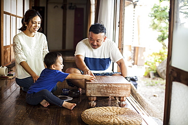 Japanese woman, man and little boy sitting on floor on porch of traditional Japanese house, playing Go, Kyushu, Japan