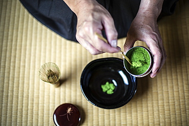 High angle close up of traditional Japanese Tea Ceremony, man spooning green Matcha tea powder into bowl, Kyushu, Japan