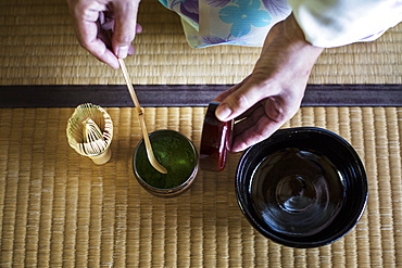 High angle close up of traditional Japanese Tea Ceremony, woman spooning green Matcha tea powder into bowl, Kyushu, Japan