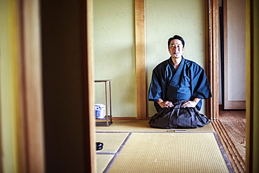 Japanese man wearing kimono kneeling on floor, on a tatami mat during tea ceremony, Kyushu, Japan