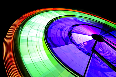 Spinning neon Ferris Wheel ride at amusement park at night, Puyallup, Washington, USA