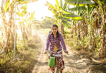 Asian woman riding bicycle on rural road