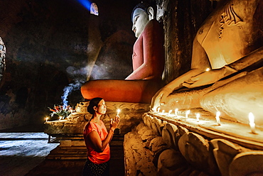 Asian woman lighting candle in temple