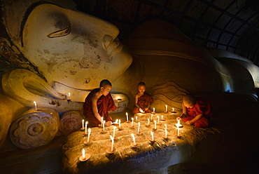 Asian monks lighting candles in temple