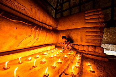 Asian girl lighting prayer candles in Buddhist temple