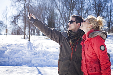 Caucasian couple taking cell phone selfie in winter