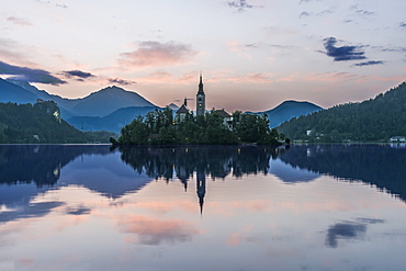 Village church and buildings reflected in still lake, Bled, Upper Carniola, Slovenia