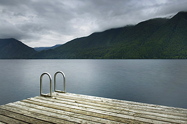 Ladder on wooden pier at still remote lake