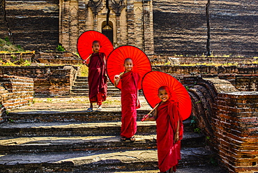 Asian monks standing under umbrellas near historic temple, Mingun, Mandala, Myanmar