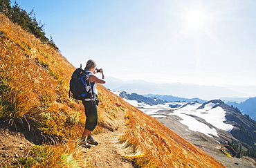 Woman taking photograph of remote mountains on hillside