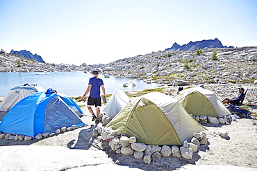 Man walking by tents at campsite in desert landscape, Leavenworth, Washington, USA