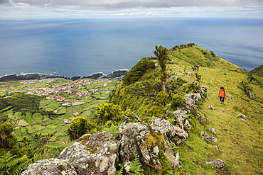 Hiker walking on hilltop path in rural landscape, Faja Grande, Flores, Portugal