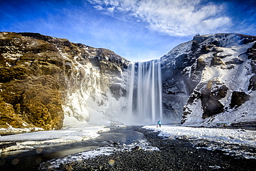 Waterfall pouring over icy cliffs in remote landscape, Skogafoss, Iceland