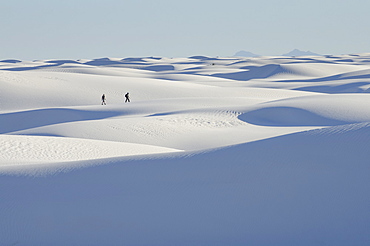 Distant people walking on snowy landscape, White Sands National Monument, New Mexico, USA