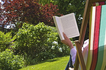 A person sitting in a deckchair, reading, Gloucestershire, England