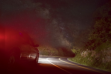 Car on winding road under starry sky, Front Royal, Virginia, USA