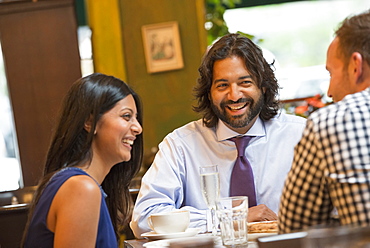 Business people out and about in the city. Three people seated around a table in a bar or cafe, having drinks. 