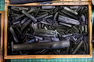 High angle close up of wooden box with a selection of artist's charcoal sticks in different sizes, Oxfordshire, England