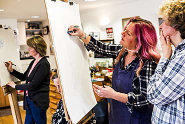 Woman standing at an easel, drawing a human leg at a life drawing glass, Oxfordshire, England